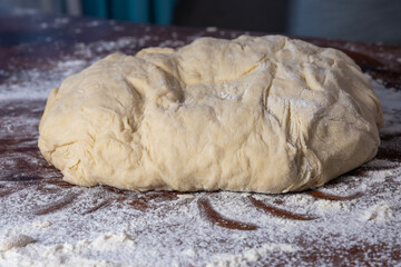 A mound of raw dough rests on a floured wooden surface, ready for shaping and baking.