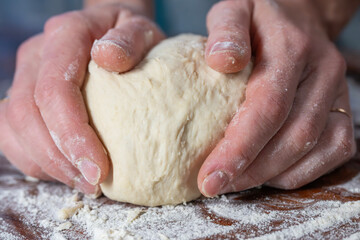 Two hands knead a ball of dough on a floured surface, capturing a tactile moment in baking.