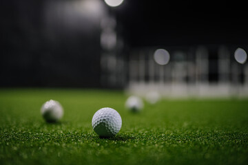 Indoor golf scene featuring multiple golf balls on artificial turf, illuminated by soft lighting, creating an inviting atmosphere for enthusiasts