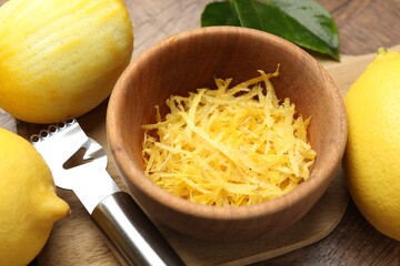 Lemon zest, fresh fruits and zester tool on wooden table, closeup