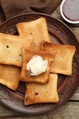 Slices of toasted bread, butter and jam on wooden table, flat lay
