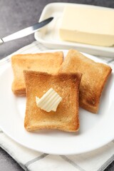 Fresh toasted bread slices with butter on grey table, closeup