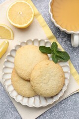 Tasty lemon cookies and fruit slices on grey table, flat lay