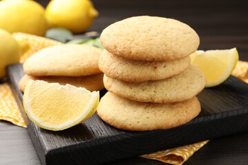 Tasty lemon cookies and fruit slices on dark wooden table, closeup