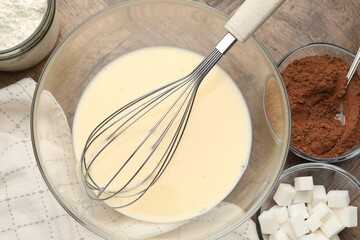 Different ingredients for dough and whisk on wooden table, flat lay