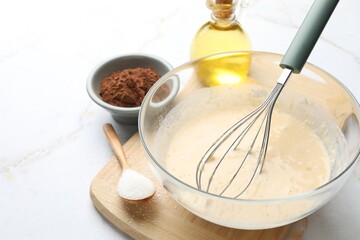 Different ingredients for dough and whisk on white marble, closeup. Space for text