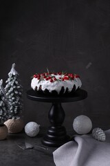 Tasty Christmas cake with cranberries, rosemary, server and festive decor on grey table