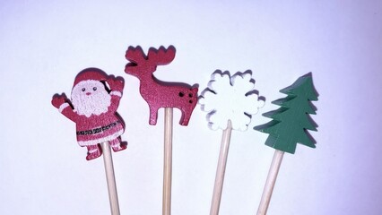 wooden santa claus reindeer snowflake and christmas tree figures on sticks against white background