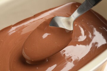 Taking liquid chocolate dough with spoon from baking dish, closeup