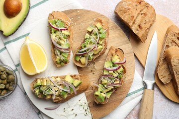 Delicious bruschettas with avocado, onion and microgreens served on light table, flat lay