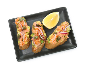 Delicious bruschettas with salmon, avocado, capers, onion and lemon slice isolated on white, top view