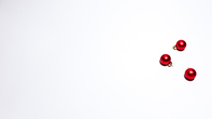 Minimal Christmas card design with three red ornaments arranged on the right side, leaving a wide clean white space for personalized holiday messages or festive greetings.