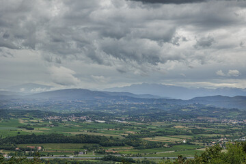 Obraz premium ambiente misto naturale ed urbano tra la pianura e le colline tra Italia e Slovenia, in estate, di pomeriggio, con cielo nuvoloso e meteo piovoso