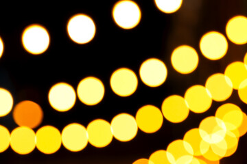 Warm yellow and white bokeh lights forming soft glowing circles against deep black background, creating cozy, atmospheric visual suitable for holiday themes, creative designs, decorative backdrops