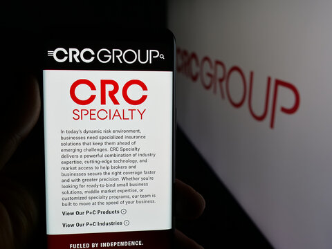 Stuttgart, Germany - 11-28-2025: Person holding smartphone with web page of US company CRC Insurance Services LLC on screen in front of logo. Focus on center of phone display.