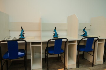 Individual lab workstations with microscopes in a study room designed for scientific research.