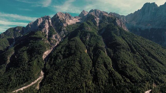 Expansive view of rugged Slovenian mountains south of Kranjska Gora, featuring dense green forests, rocky peaks, and deep alpine valleys under clear skies. 4k stock video
