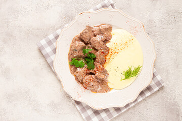 liver beef stroganoff, with mashed potatoes, on a light plate, homemade,