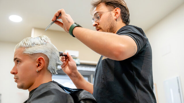 Barber applying bleach to client's hair in shop