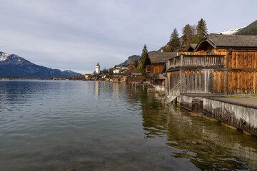 Fototapeta premium Panorama am Wolfgangssee mit Häusern aus Holz und der Kirche aus St. Wolfgang, Österreich, im Hintergrund