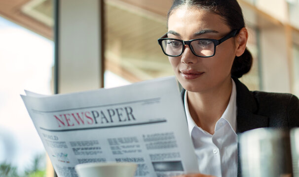 businesswoman reading newspaper and drinking coffee