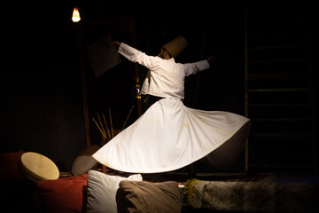 The image of a dervish performing a whirling dervish dance against a dark backdrop.