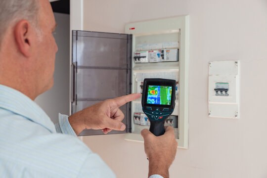 Electrician checking fuse box with thermal imaging camera