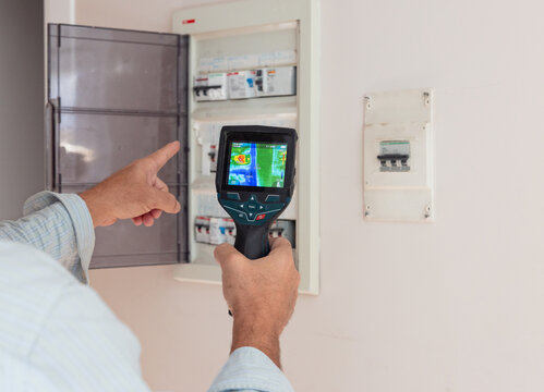 Electrician performing thermal inspection on fuse box circuits