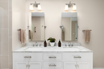 An elegant bathroom with brown walls, marble countertop on a white vanity, chrome faucets, and...