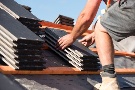 Roofing works in progress as new covering of  tiled roof done by roofer