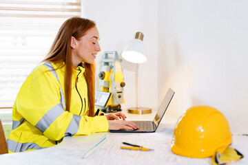 Young female professional architect working on architectural plans in office