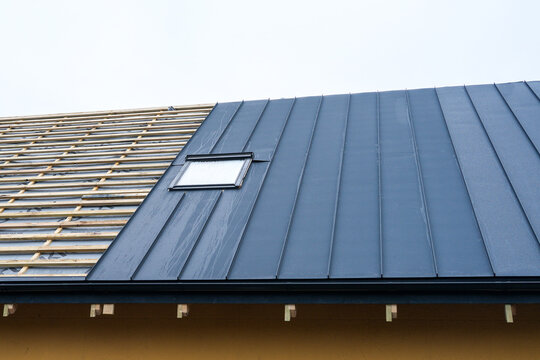 Modern metal roof installation with skylight on residential house under construction