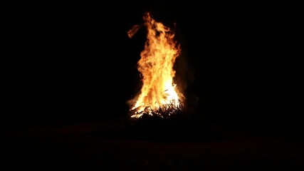 bonfire flames rising into dark night sky (bon fire flame orange yellow red glow glowing ember) sticks wood stick brush wooden fuel summer ceremony celebration enormous huge rise heat campfire camping