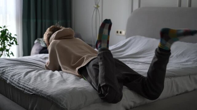Young boy in pajamas playing on bed, moving legs