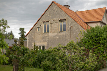 A charming rustic house beautifully surrounded by lush greenery, all beneath a soft, cloudy sky in the background