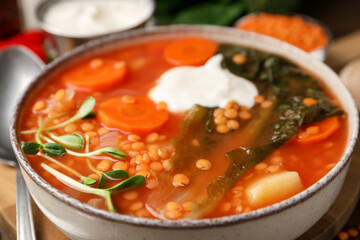 Tasty lentil soup with sour cream in bowl on table, closeup