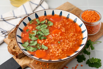 Tasty lentil soup in bowl served on light table, closeup