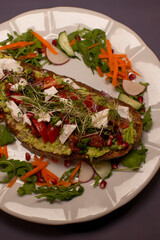 creamy avocado toast topped with goat cheese, sun dried tomatoes, pomegranate seeds and microgreens, served with arugula salad