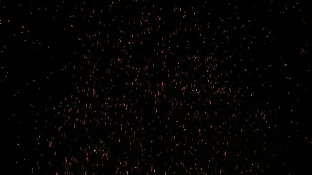 sparks and embers flying in the air from a large bonfire (campfire spark ember glow particles) coal wood burning flame particulates soot floating night fire glowing flames