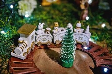 Christmas nativity scene ornaments featuring a miniature train and tree, beautifully arranged with festive lights, creating a warm holiday atmosphere and joyful celebration