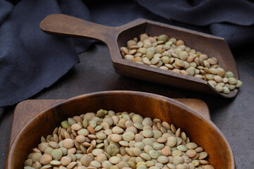 Pile lentil in wooden spoon isolated on Woden background. Top view.