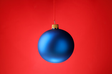 One Christmas ball hanging against red background, closeup