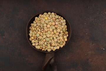 Pile lentil in wooden spoon isolated on Woden background. Top view.