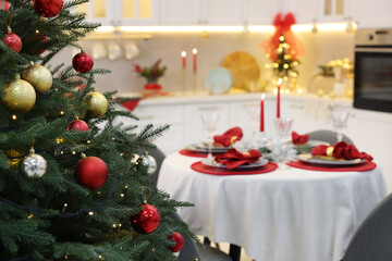 Christmas tree and festive table setting in kitchen, selective focus with space for text. Interior design