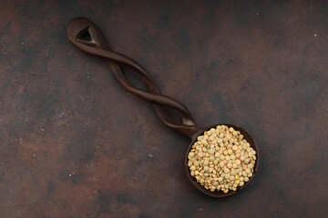 Pile lentil in wooden spoon isolated on Woden background. Top view.