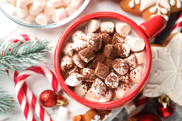 Tasty cocoa with marshmallows, candy canes, gingerbread cookies and Christmas decor on table, flat lay