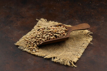 Pile lentil in wooden spoon isolated on Woden background. Top view.