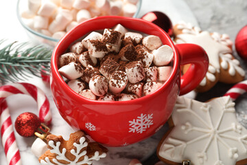 Tasty cocoa with marshmallows, candy canes, gingerbread cookies and Christmas decor on table,...