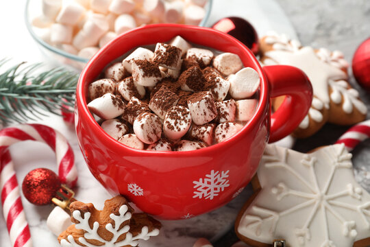 Tasty cocoa with marshmallows, candy canes, gingerbread cookies and Christmas decor on table, closeup - Powered by Adobe