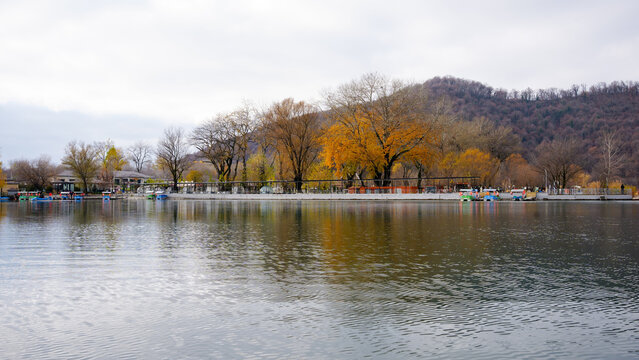 Nohur Lake autumn reflections - Calm waters of Nohur Lake reflecting autumn trees and surrounding hills under overcast skies. Nohur Lake, Azerbaijan